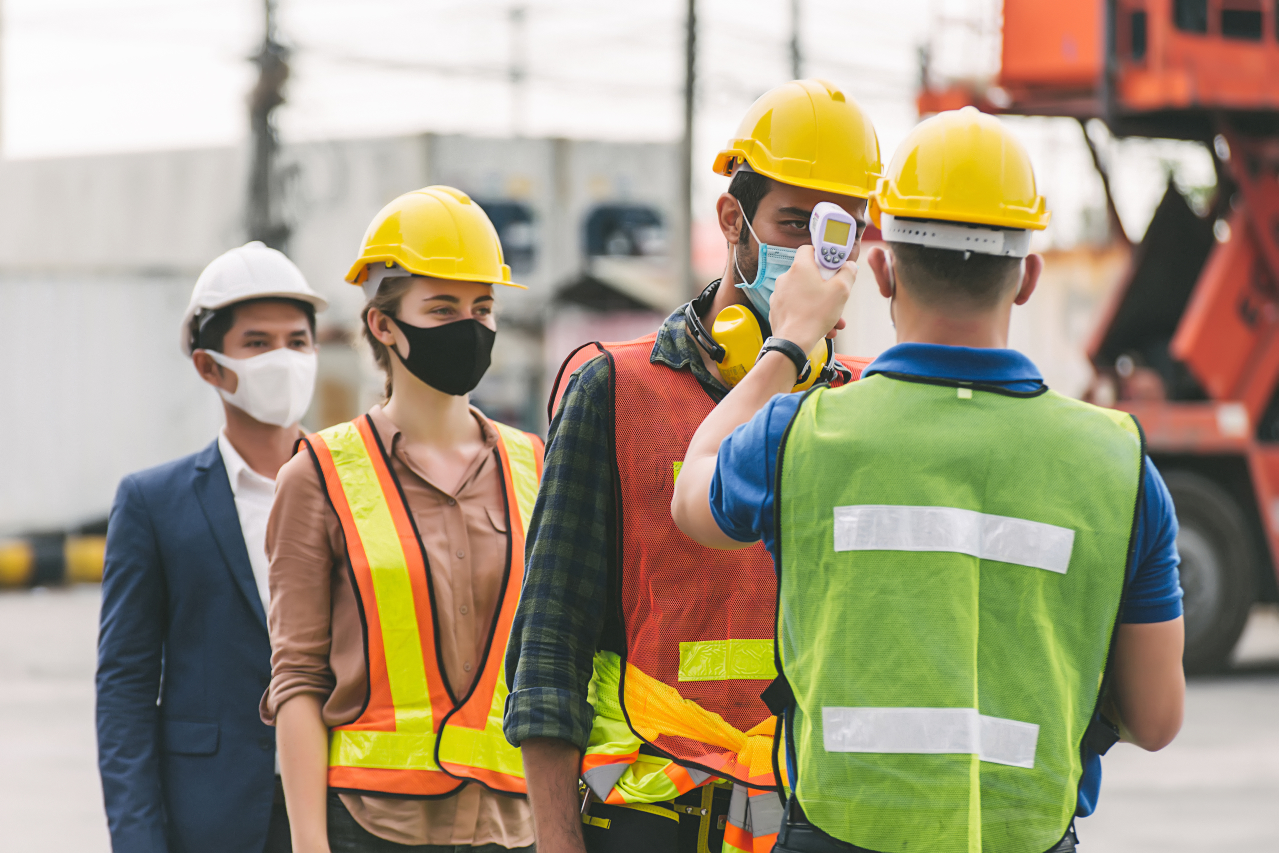 Workers wearing safety gear taking temperature