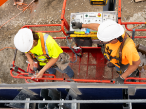 Builders Association workers on electric lift wearing neon shirts and hard hats outside