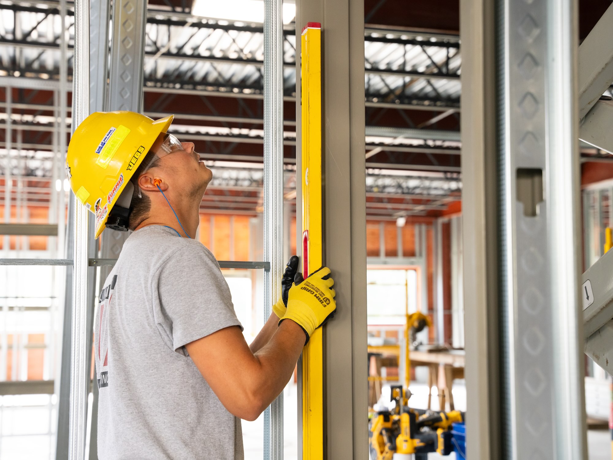 Worker measuring metal beam wearing hard hat